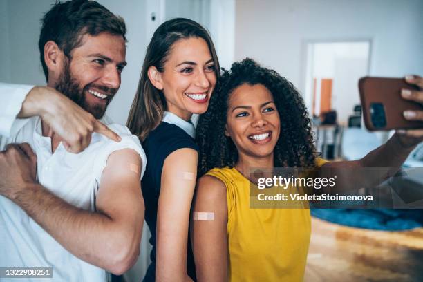 friends showing their arms after getting vaccinated. - african american band aids stock pictures, royalty-free photos & images