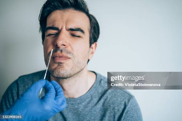 doctor taking nose swab test from young man. - nasal swab stock pictures, royalty-free photos & images