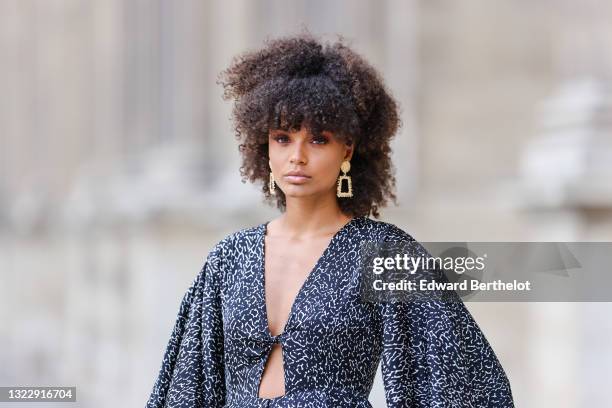 Alicia Aylies wears gold and rhinestones earrings, a black and white print pattern V-neck oversized flowing jumpsuit, on June 08, 2021 in Paris,...