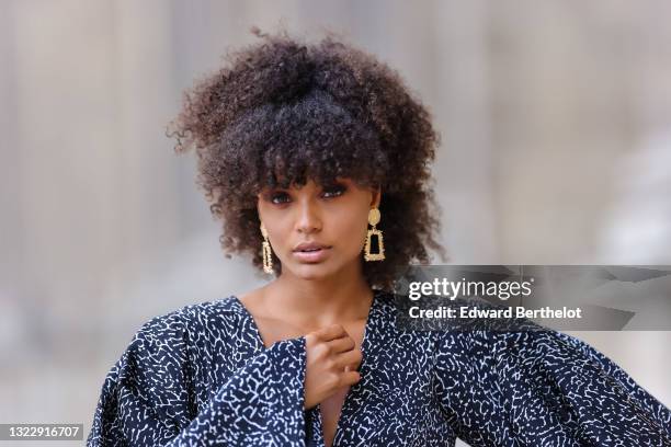 Alicia Aylies wears gold and rhinestones earrings, a black and white print pattern V-neck oversized flowing jumpsuit, on June 08, 2021 in Paris,...