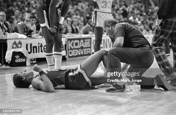 The Seattle Supersonics trainer examines injured guard Dennis Johnson during an NBA basketball game against the Denver Nuggets at McNichols Arena on...
