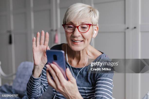 senior woman is communicating on video call in bedroom - telemedicine choicepix stock pictures, royalty-free photos & images