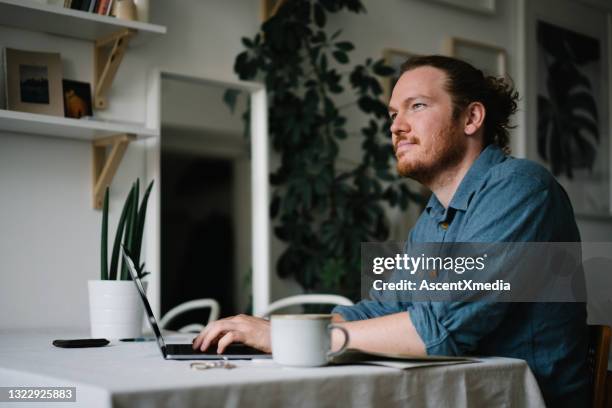 young man works online at household kitchen table - connected mindfulness work stock pictures, royalty-free photos & images