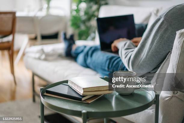de jonge mens werkt online van woonkamer - man living room stockfoto's en -beelden