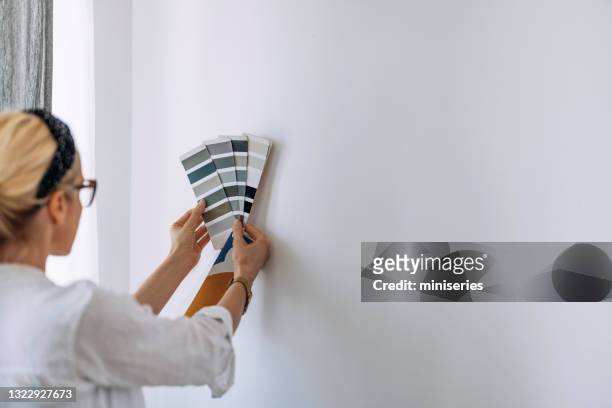 junge frau hält farbkarte auf weißer wand - farbfächer stock-fotos und bilder
