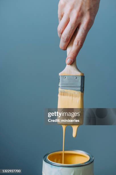 woman testing yellow paint with paintbrush - pintar imagens e fotografias de stock