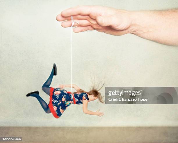 man's hand dangling a miniature woman on a string. - ditador imagens e fotografias de stock