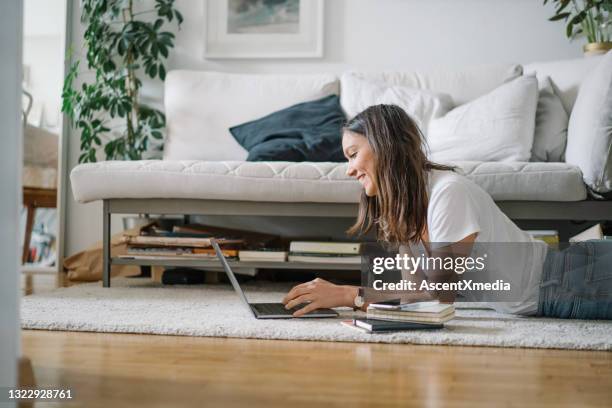 young woman works on laptop from living room - connected mindfulness work stock pictures, royalty-free photos & images