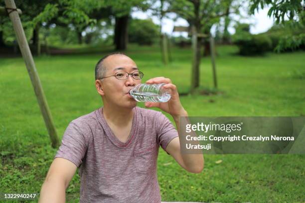 japanese man dring purified water in a bottle - 息抜き ストックフォトと画像