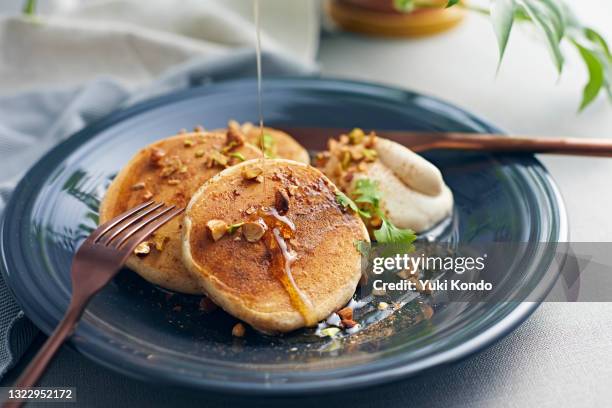 drizzle maple syrup over pancakes. - syrup drizzle stock pictures, royalty-free photos & images