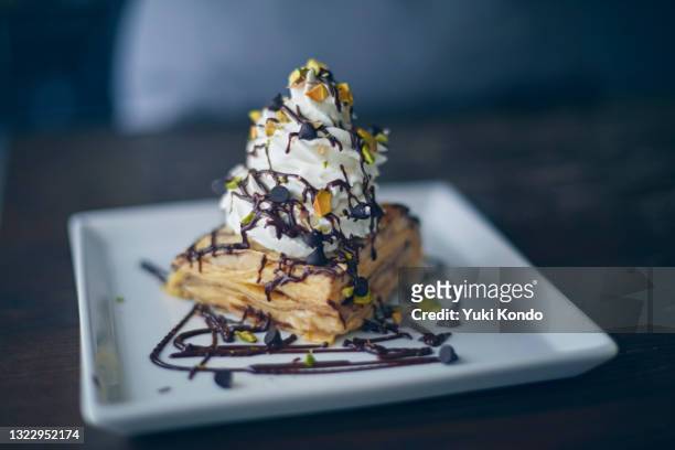mille crepes with whipped cream topped with pistachio and chocolate. - vierkant bord stockfoto's en -beelden