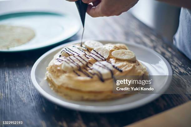 a woman's hand making a mille crepe. - dessert topping stock pictures, royalty-free photos & images