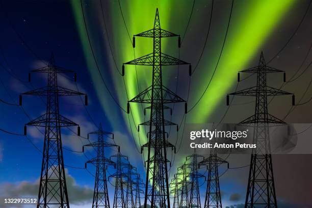 high voltage towers at the northern lights background. power lines against the polar sky - elektriciteitsnet stockfoto's en -beelden