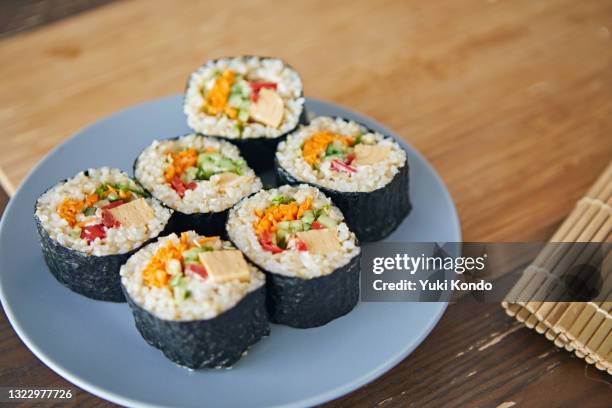 sushi made rolled in nori seaweed with a core of filling. - sushi brown rice stock pictures, royalty-free photos & images