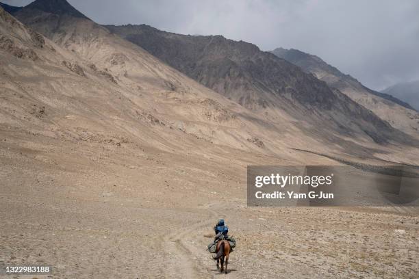 Benazir, a conservationist, rides her horse to collect camera traps on May 20, 2021 in Issyk Kul, Kyrgyzstan. Sarychat-Ertash Nature Reserve was...