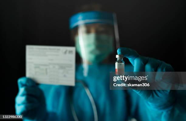 doctor wearing surgical gloves and preparing the coronavirus covid-19 vaccine (2019-ncov) first coronavirus vaccine found in the world and holding vaccination passport or vaccination card - co found stock pictures, royalty-free photos & images