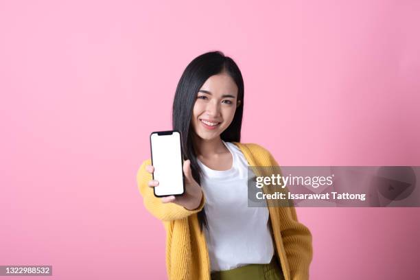 young beautiful woman holding blank screen smart phone on pink background - frau mit handy screen stock-fotos und bilder