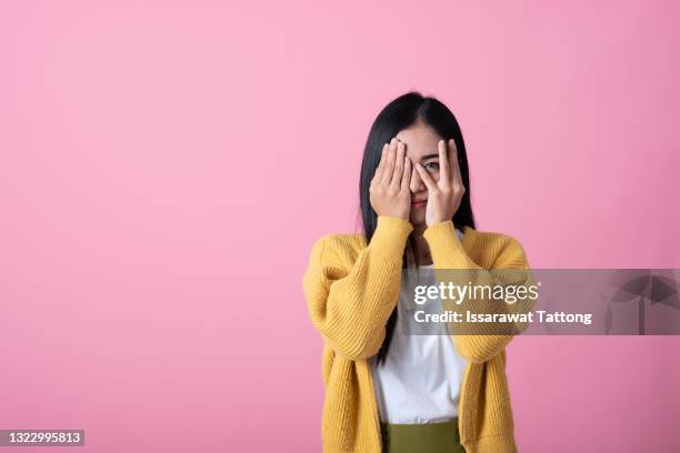 a picture of a scared woman covering her eyes over pink background - gömma bildbanksfoton och bilder