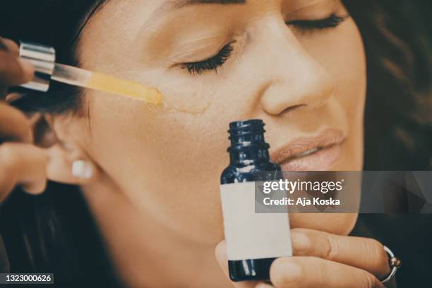 mujer aplicando suero facial. - imagen virada fotografías e imágenes de stock