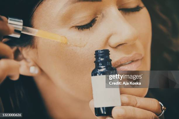 woman applying face serum. - toned image stock pictures, royalty-free photos & images