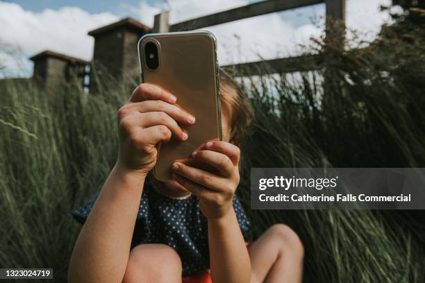 child take a photo with a mobile phone - girl grabbing phone foto e immagini stock