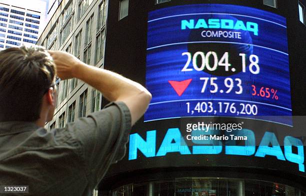 Tourist in Times Square views a Nasdaq ticker July 6, 2001 in New York City. The major U.S. Stock indexes tumbled to 10-week lows with the the Nasdaq...