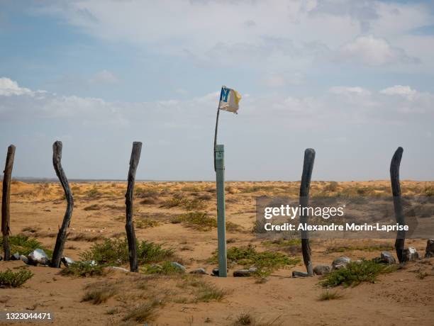 some logs built as a fence with a broken flag in a desert near a bay in bahia honda, la guajira, colombia - wooden stick stock pictures, royalty-free photos & images