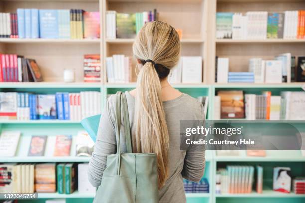 femme adulte regardant des livres sur l’étagère dans la librairie - librairie photos et images de collection