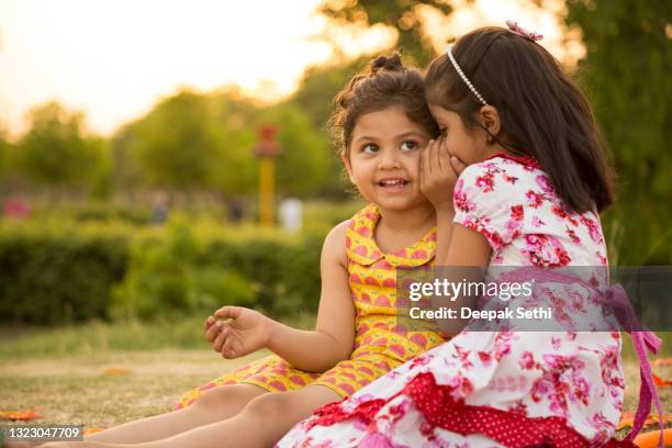 süße schild mädchen spielen im park:- stockfoto - child whispering stock-fotos und bilder