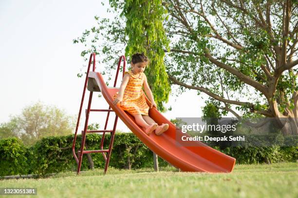 Mixed race boy sliding down slide in playground - Stock Photo