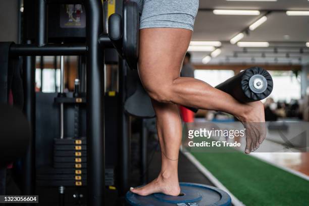 sección baja de la pierna de una mujer madura mientras entrena con el equipo de la máquina de la pierna - female muscular calves fotografías e imágenes de stock