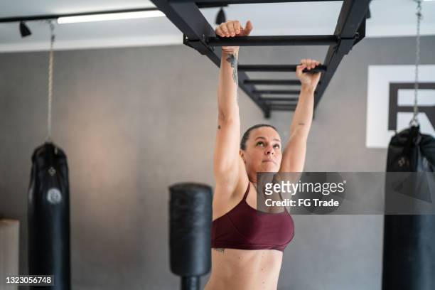 femme faisant de l’exercice sur des barres de singe dans la salle de gym - cage à poules photos et images de collection