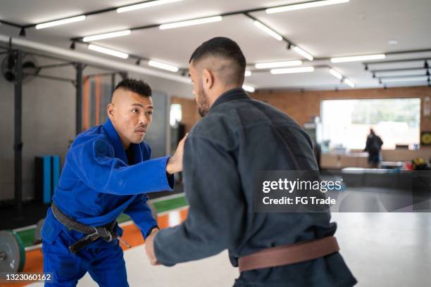 two male judo practitioners fighting in a gym - teach to fight stock pictures, royalty-free photos & images