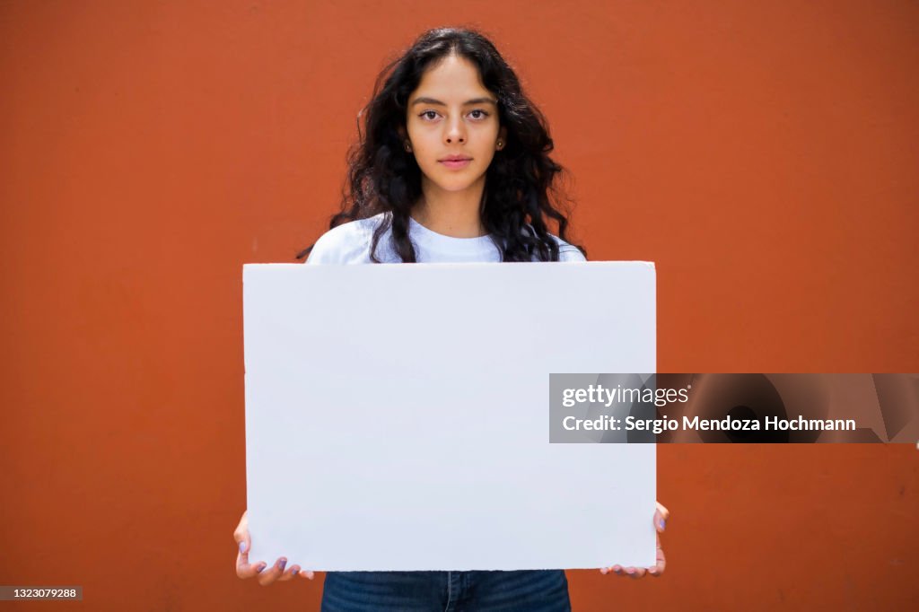 Young Latino woman holding a blank sign