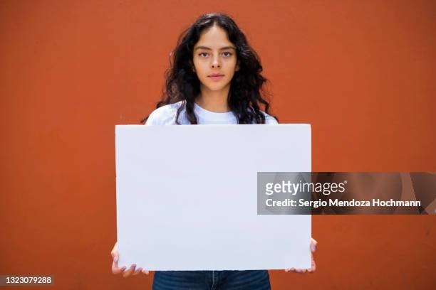 young latino woman holding a blank sign - placard 個照片及圖片檔