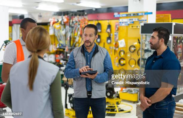 winkelmanager die met een groep werknemers bij een ijzerhandel spreekt - shop assistant stockfoto's en -beelden