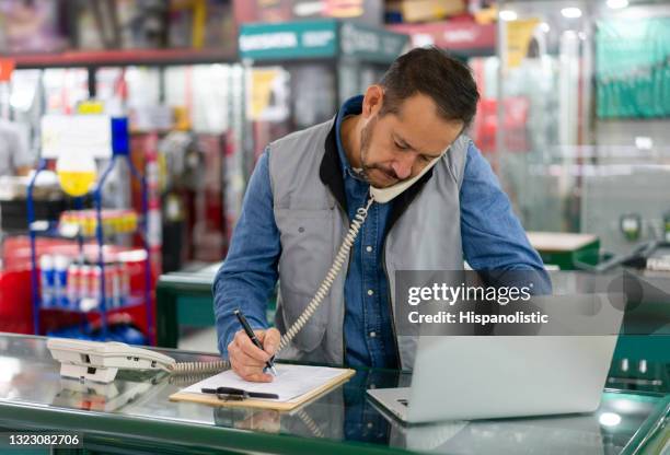 business owner at a hardware store and making some phone calls - loja de ferragens imagens e fotografias de stock