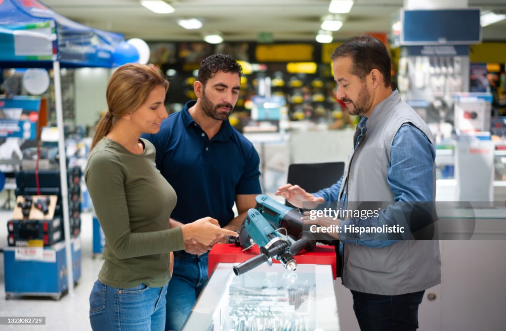 Paar kaufen Werkzeuge in einem Baumarkt und suchen Rat von einem Verkäufer