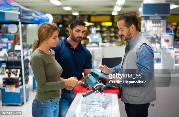 couple buying tools at a hardware store and seeking for advice from a salesman - hardware shop stock pictures, royalty-free photos & images