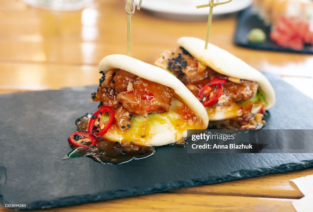 Asian traditional meal: bao with chicken and chili pepper on restaurant table