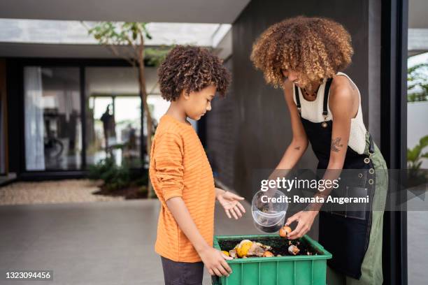 african american young woman and her younger brother making compost from leftovers. sustainability concept. - compost stock pictures, royalty-free photos & images