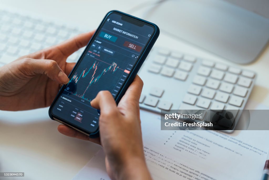 Close-up Shot of an Anonymous Woman Holding a Smartphone with a Stock Market Graph on Screen