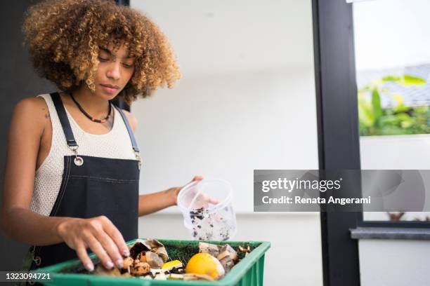 african american young woman making compost from leftovers. sustainability concept. - compost stock pictures, royalty-free photos & images