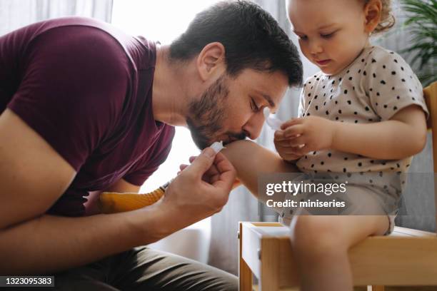 padre amorevole che bacia il ginocchio ferito della figlia piccola - leg kissing foto e immagini stock