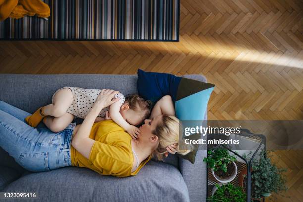 top view of beautiful mother with little daughter sleeping on sofa - tired mother stock pictures, royalty-free photos & images