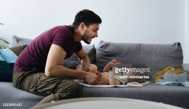 cute baby girl getting her diaper changed on couch - nappy change stock pictures, royalty-free photos & images