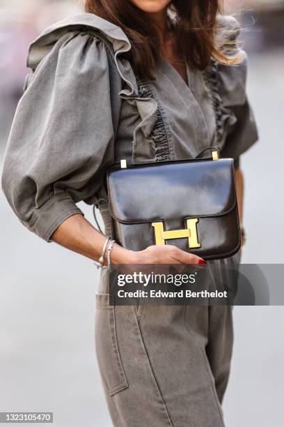 Therese Hellström wears black sunglasses, a gray denim puffy sleeves / V-neck / belted rolled-up / jumpsuit, a dark brown shiny leather Constance...