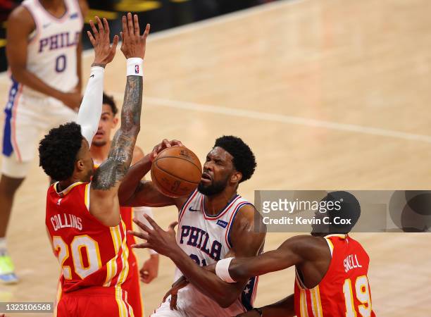 Joel Embiid of the Philadelphia 76ers draws a foul from Tony Snell of the Atlanta Hawks as he drives against John Collins during the first half of...