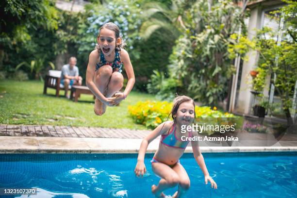 irmãs divertidas pulando na piscina da família - salta argentina - fotografias e filmes do acervo
