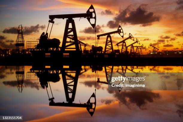 ölpumpen und bohrinsel bei sonnenuntergang am meer - oil and gas stock-fotos und bilder